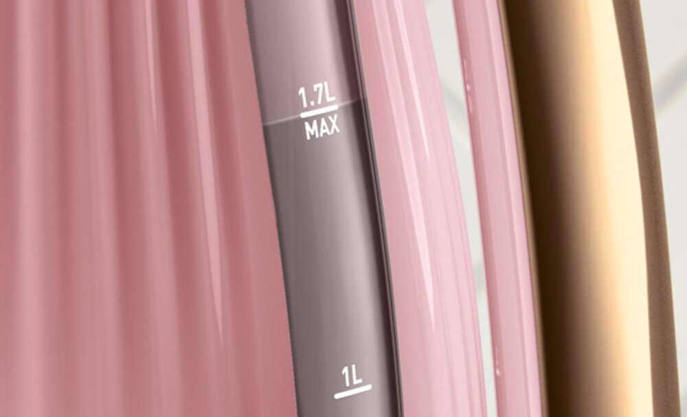 Zbliżenie na różowy czajnik z przezroczystym wskaźnikiem poziomu wody, na którym widoczne są oznaczenia \'1.7L MAX\' i \'1L\'.