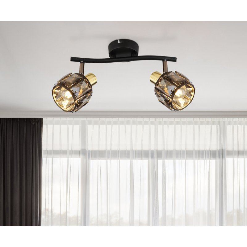 Lampa sufitowa z dwoma źródłami światła, posiada czarne matowe i złote matowe wykończenie oraz szklane przydymione kryształy. W tle widoczne są zasłony i okno.