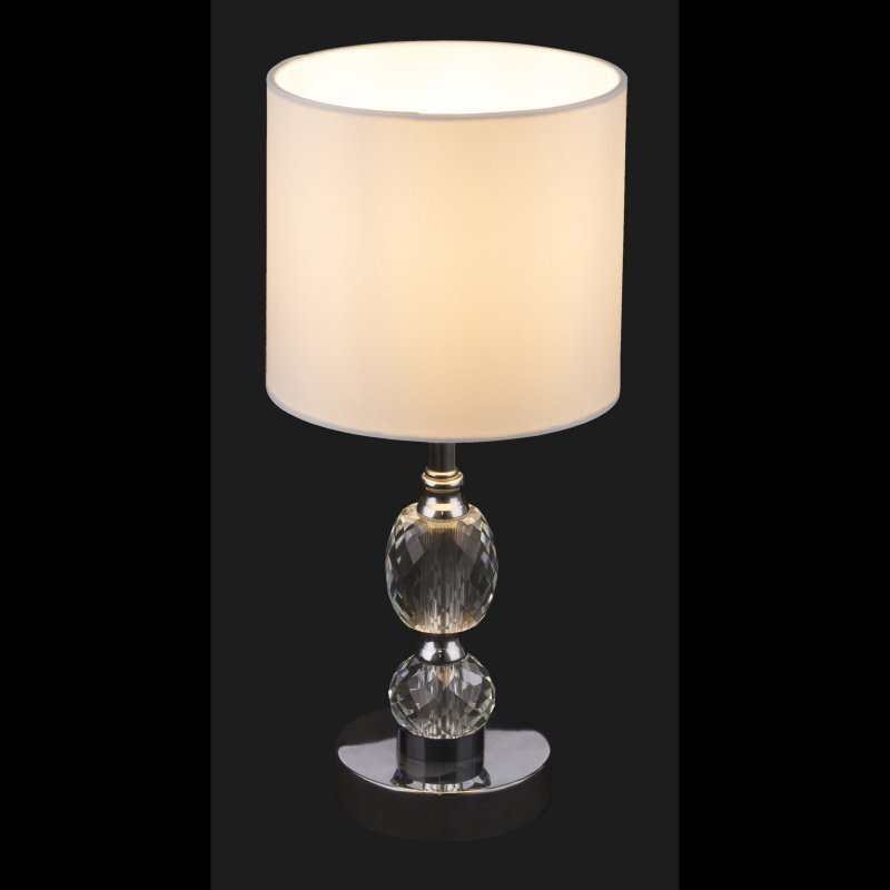 Lampa stołowa z białym abażurem i podstawą z przezroczystego, kryształowego szkła na chromowanej podstawie. Lampa ma klasyczny design i jest wyposażona w wyłącznik.