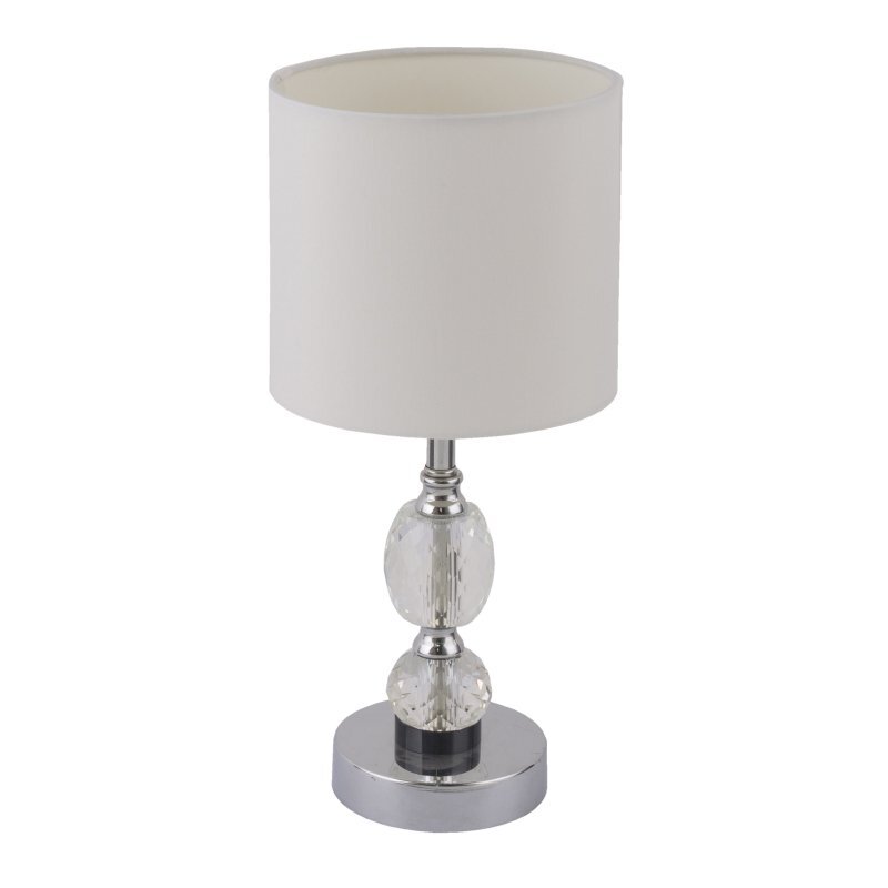 Lampa stołowa z białym abażurem i chromowaną podstawą ozdobioną kryształowymi elementami. Posiada cylindryczny kształt i wyłącznik na podstawie.