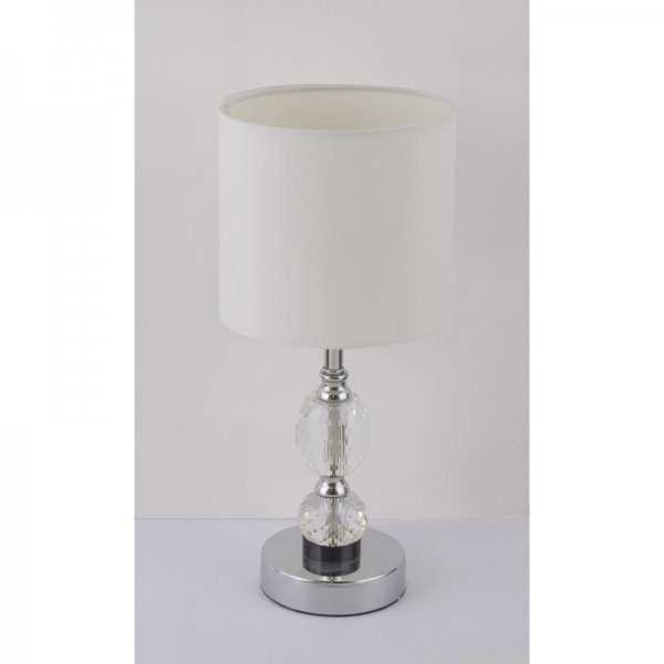 Lampa stołowa z białym abażurem i chromowaną podstawą ozdobioną kryształowymi elementami. Posiada cylindryczny kształt i wyłącznik.