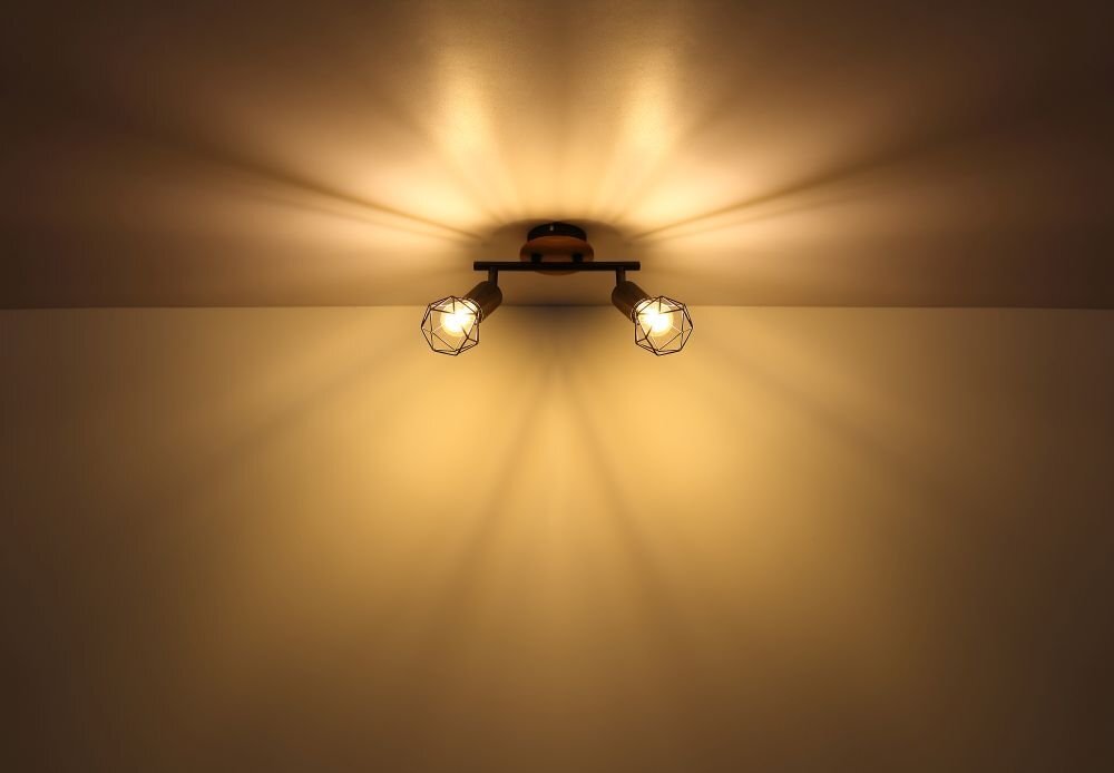 Na suficie zamontowana jest lampa sufitowa z dwoma żarówkami w metalowych oprawach, emitująca ciepłe światło. Światło tworzy wzory na suficie i ścianie.