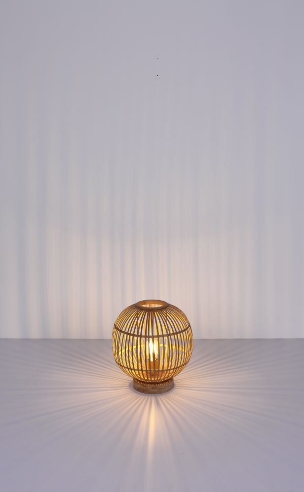Na obrazie widoczna jest lampa stołowa z naturalnego bambusa, emitująca ciepłe światło, które tworzy wzory na powierzchni. Lampa ma kształt kuli z ażurową konstrukcją.