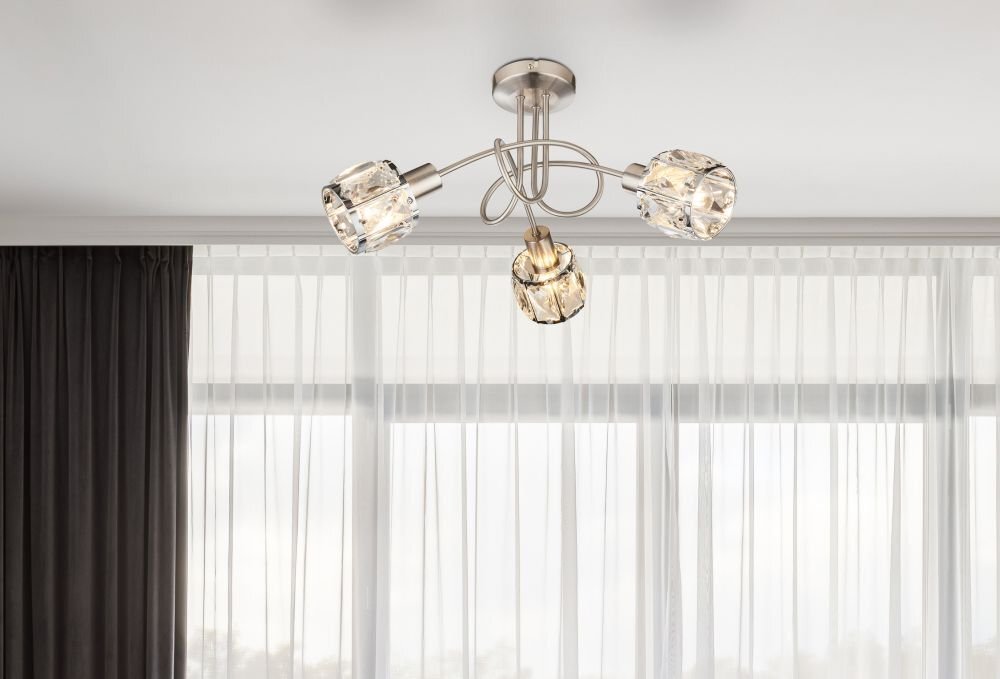 Na obrazie widoczna jest lampa sufitowa z trzema źródłami światła, wykonana z chromowanej satyny i szklanych kryształów. W tle znajdują się zasłony i okno.