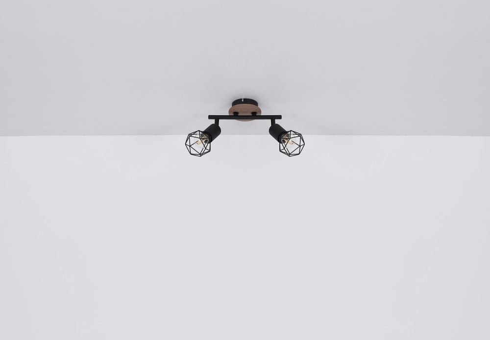 Na obrazie widoczna jest lampa sufitowa z trzema regulowanymi reflektorami w czarnym kolorze, wykonana z metalu i drewna. Reflektory mają geometryczne klosze i są zamontowane na prostokątnej podstawie przymocowanej do sufitu.