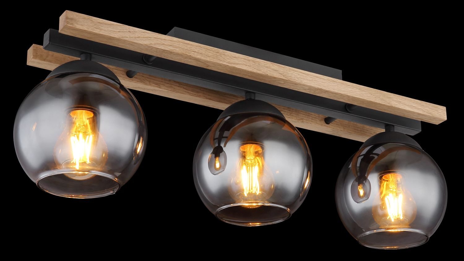 Lampa sufitowa z trzema szklanymi kloszami w kształcie kul, zamontowana na drewnianej listwie. Każdy klosz zawiera żarówkę emitującą ciepłe, żółte światło.
