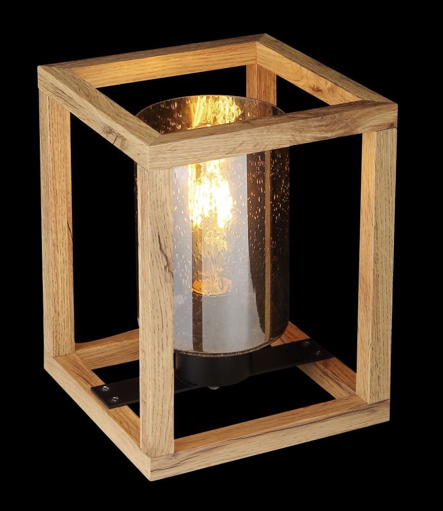 Lampa stołowa z drewnianą ramą w kształcie sześcianu, wewnątrz której znajduje się szklany klosz z widoczną żarówką. Klosz jest przydymiony, a światło żarówki tworzy ciepły efekt świetlny.