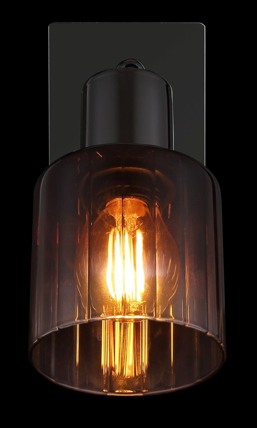 Lampa z przezroczystym, ciemnym kloszem, przez który widać świecącą żarówkę. Klosz jest zamocowany na prostokątnej, czarnej podstawie.