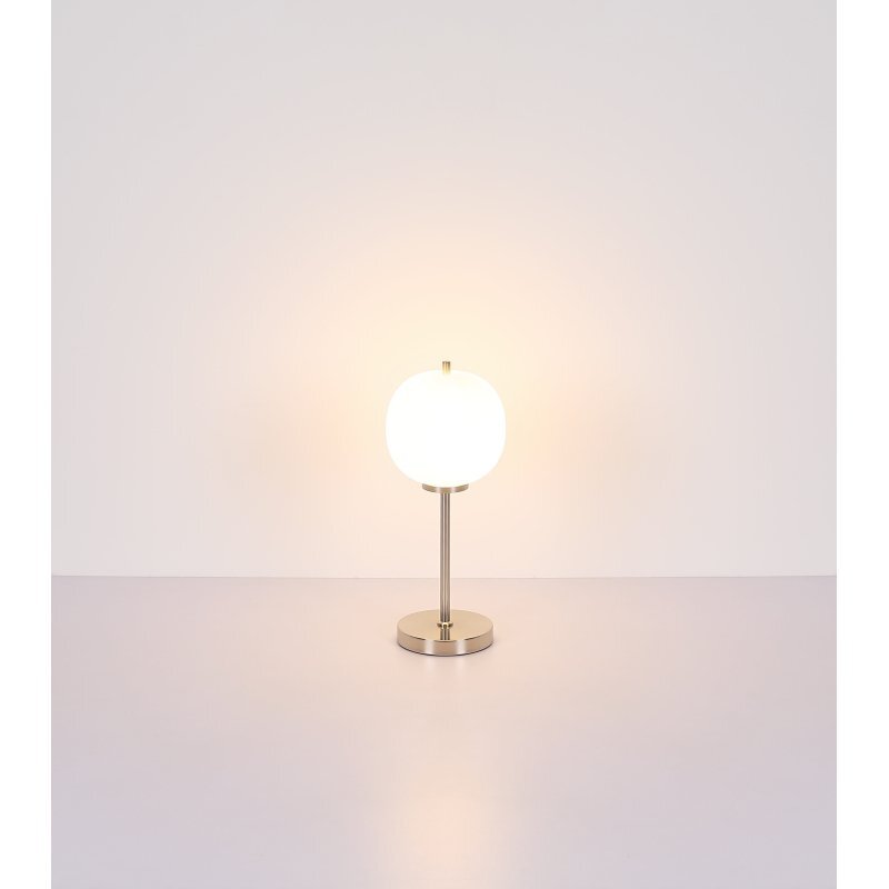 Na obrazie widoczna jest lampa stołowa z matowym niklowym wykończeniem i opalowym szklanym kloszem, stojąca na gładkiej powierzchni. Lampa emituje ciepłe, rozproszone światło.