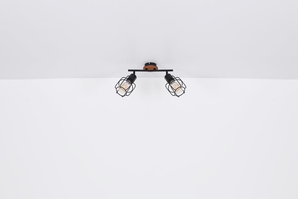 Na obrazie widoczna jest lampa sufitowa z dwoma regulowanymi reflektorami w czarnym kolorze z metalowymi osłonami. Elementy mocujące wykonane są z brązowego drewna.