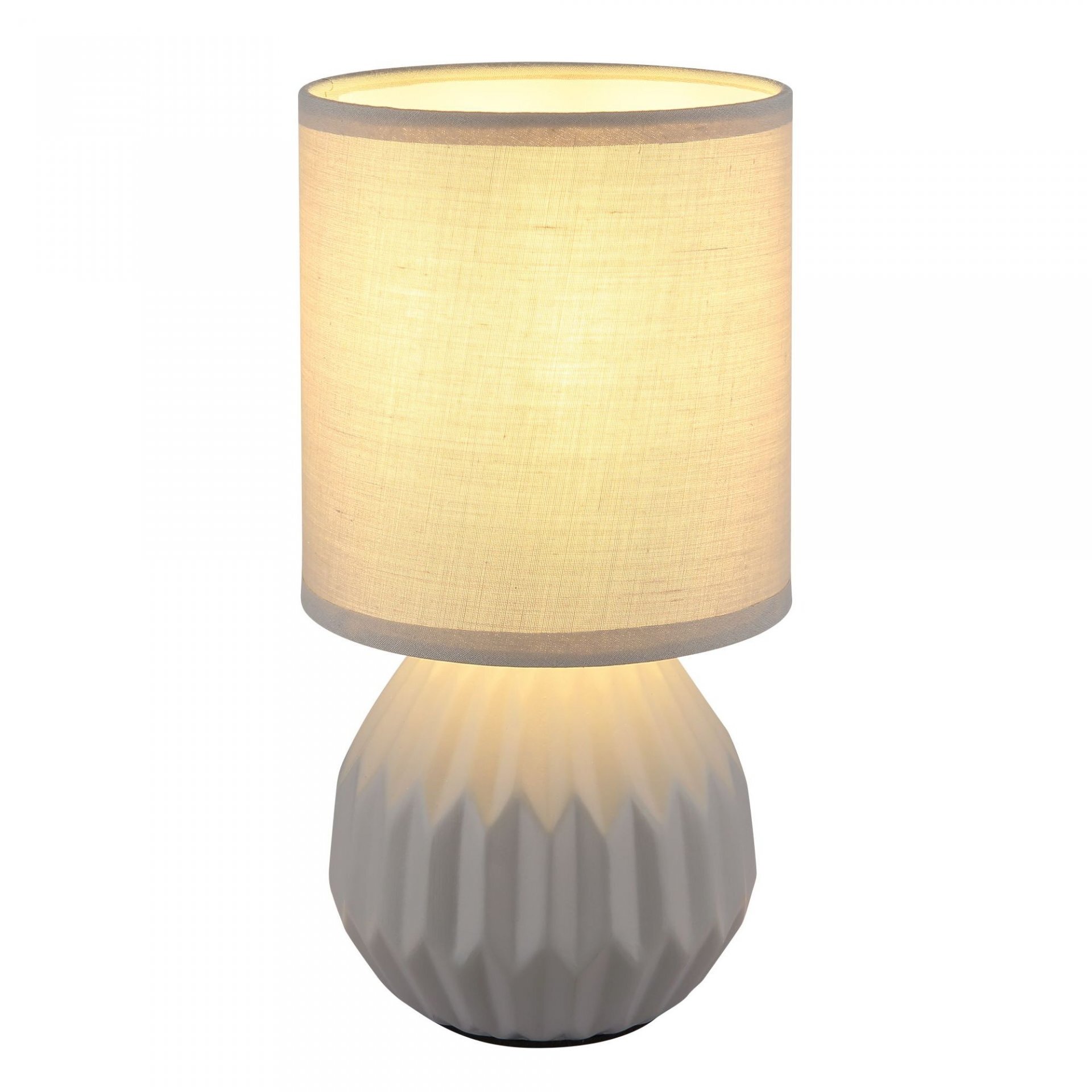 Lampa stołowa z cylindrycznym, jasnym abażurem i żłobioną, ceramiczną podstawą w kolorze szarym. Światło delikatnie przenika przez materiał abażuru, tworząc przytulną atmosferę.