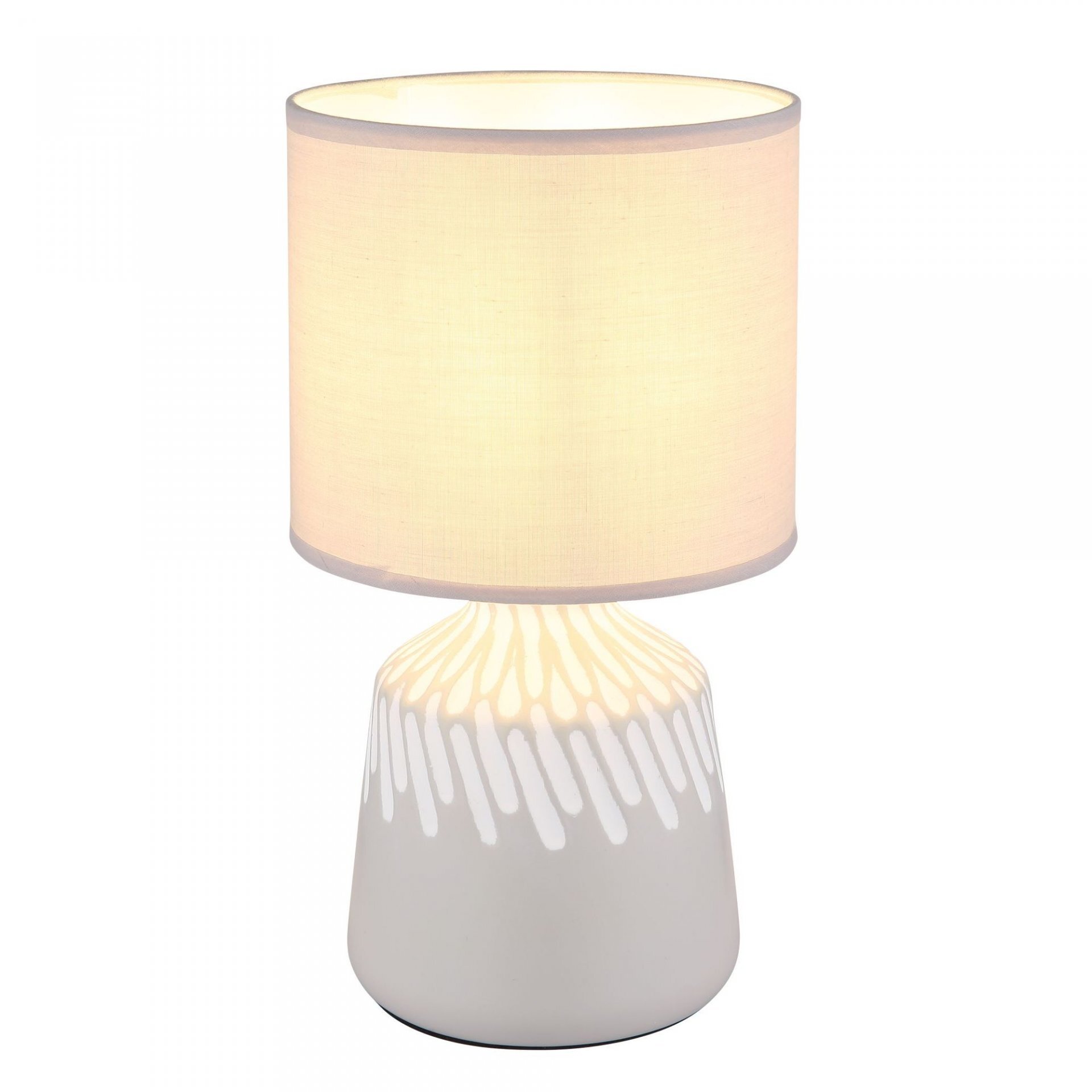 Na obrazie widoczna jest lampa stołowa z białym, cylindrycznym abażurem i ozdobną podstawą w białym kolorze z wzorem przypominającym krople. Lampa emituje ciepłe, rozproszone światło.
