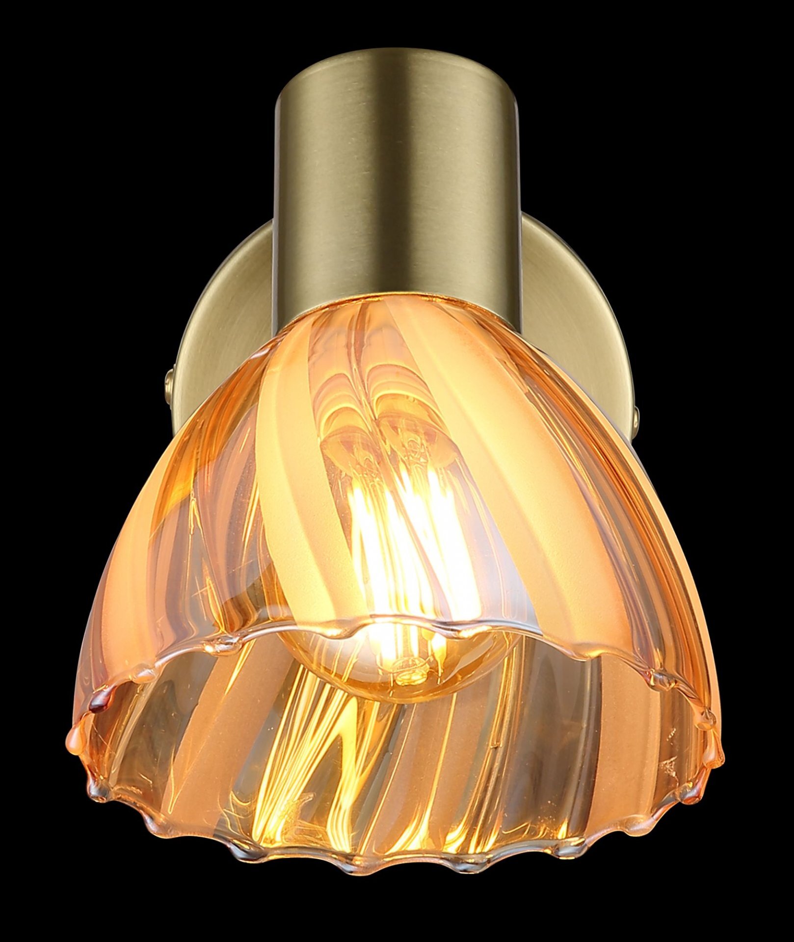 Lampa reflektorowa z kloszem w kolorze bursztynowym, zamontowana na metalowej podstawie w kolorze złotym. Klosz ma falisty wzór i przepuszcza ciepłe światło żarówki.