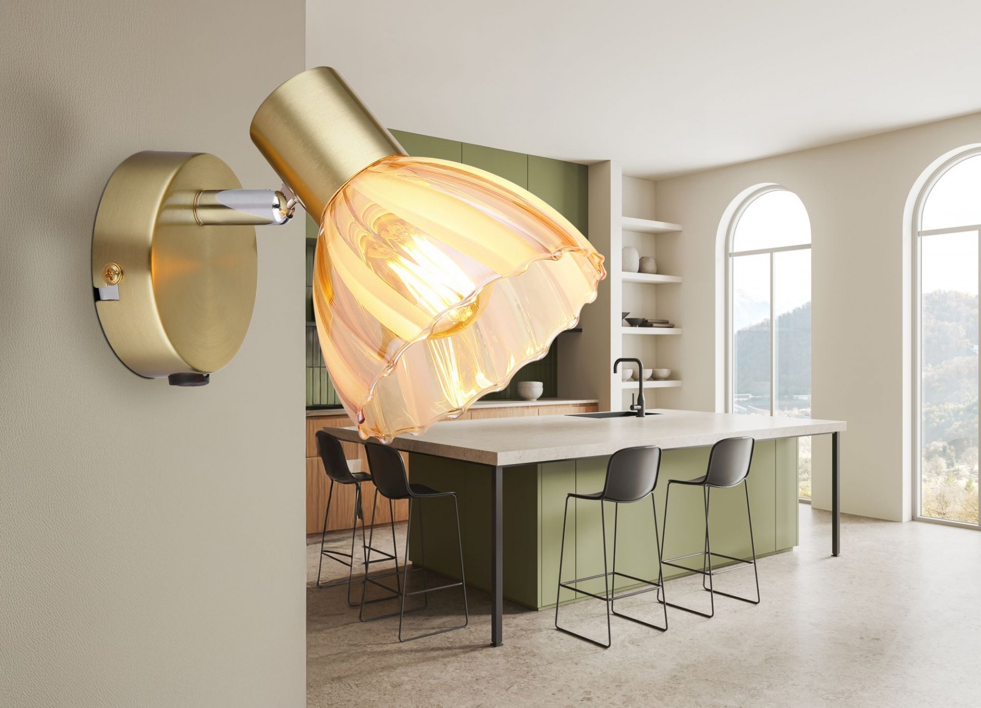 Na ścianie zamontowana jest lampa reflektor z metalowym korpusem i szklanym kloszem w kolorze złotym. W tle widać nowoczesną kuchnię z wyspą i wysokimi krzesłami.