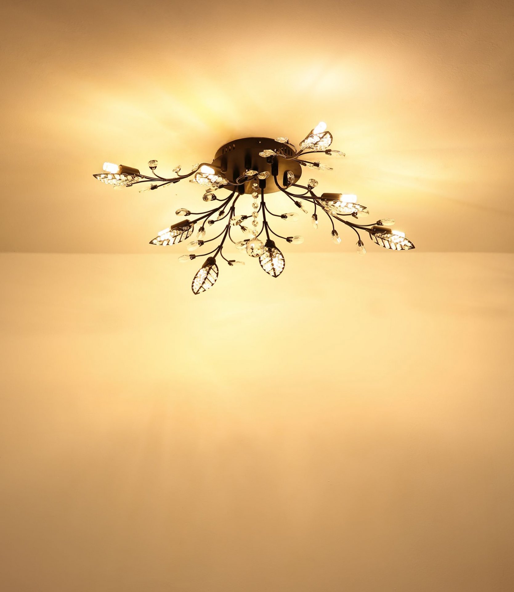 Lampa sufitowa z dekoracyjnymi elementami w kształcie liści i gałązek, emitująca ciepłe, rozproszone światło. Konstrukcja jest zamontowana na suficie, tworząc efektowne oświetlenie wnętrza.