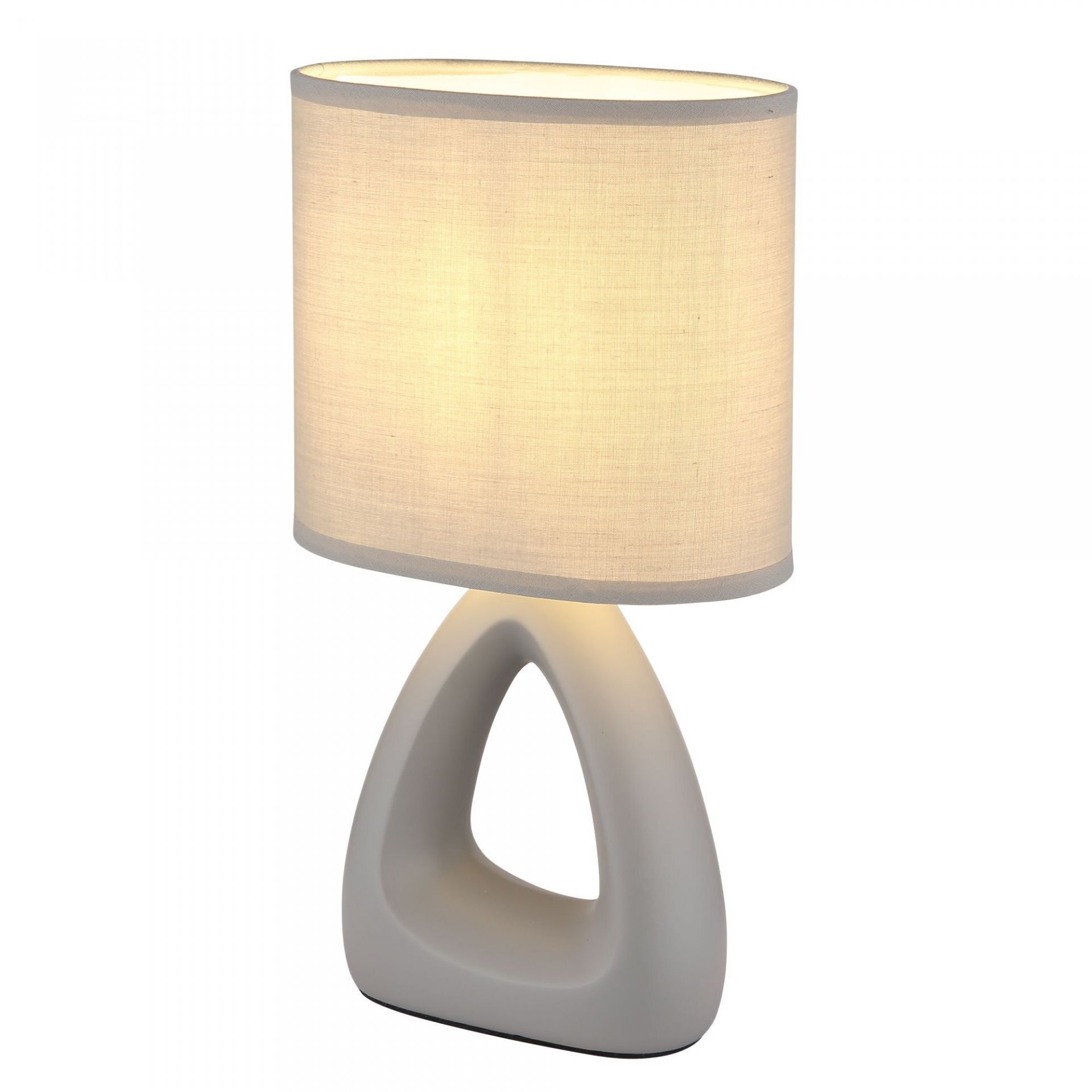 Nowoczesna lampa stołowa z owalnym abażurem w jasnym kolorze i podstawą w kształcie trójkąta z otworem pośrodku. Lampa emituje ciepłe, rozproszone światło.