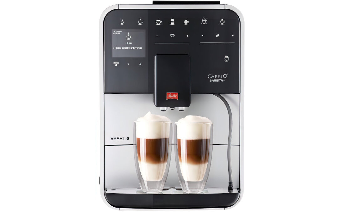 Ekspres do kawy z wyświetlaczem pokazującym tekst \'Please select your beverage\' oraz dwoma filiżankami z kawą i mleczną pianką. Na urządzeniu widoczne jest logo \'CAFFEO BARISTA\' oraz symbol producenta.