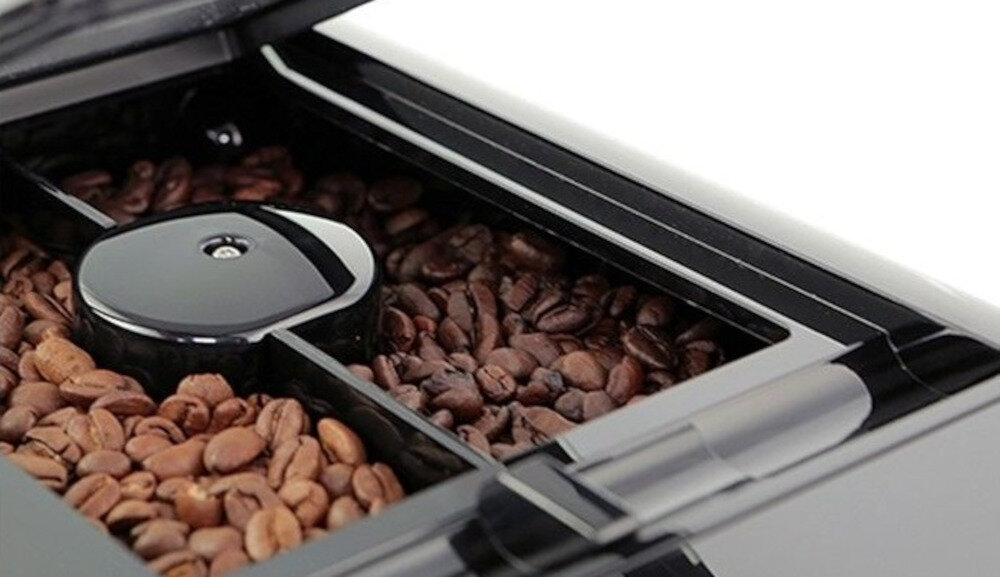Zbliżenie na pojemnik z ziarnami kawy w ekspresie do kawy, z widocznym podziałem na dwie sekcje.
