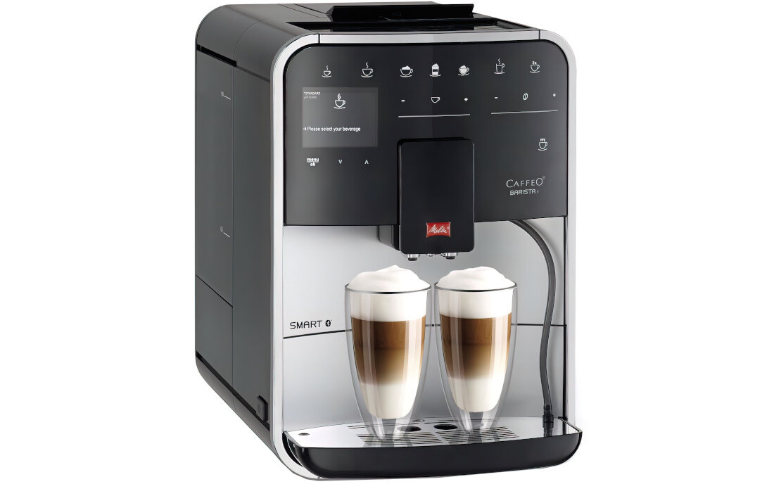 Ekspres do kawy z panelem dotykowym i dwoma szklankami z kawą mleczną. Na panelu widoczne są ikony różnych napojów oraz logo \'Melitta\'.