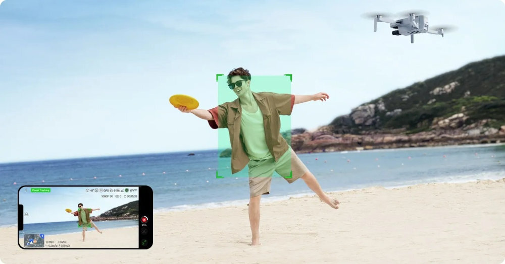 Osoba na plaży rzuca frisbee, a w tle unosi się dron. Na ekranie telefonu widoczny jest podgląd z kamery drona.