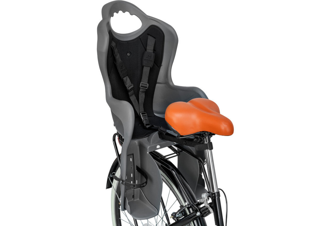 Fotelik rowerowy w kolorze grafitowo-czarnym z pomarańczowym siedziskiem, zamontowany na tylnym bagażniku roweru. Posiada pasy bezpieczeństwa i otwór na uchwyt w górnej części oparcia.