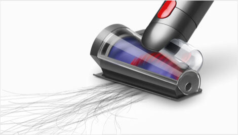 Obraz przedstawia końcówkę odkurzacza z przezroczystą obudową, w której widoczny jest niebieski i czerwony element. Końcówka zbiera długie, cienkie włosy z powierzchni.