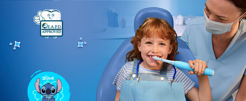 Dziecko siedzi na fotelu dentystycznym, trzymając szczoteczkę do zębów z motywem Stitch. Obok widoczny jest symbol z napisem \'E.A.P.D. APPROVED\'.