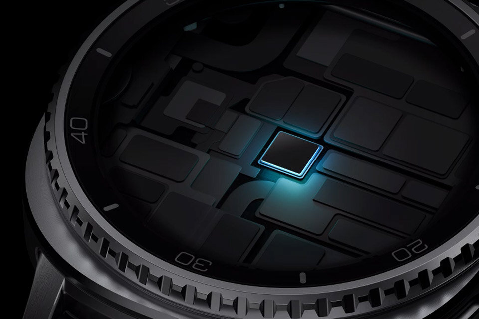 Zbliżenie na tarczę zegarka z widocznymi oznaczeniami liczbowymi i podświetlonym centralnym elementem. Tarcza ma ciemny kolor z delikatnym niebieskim podświetleniem w centrum.