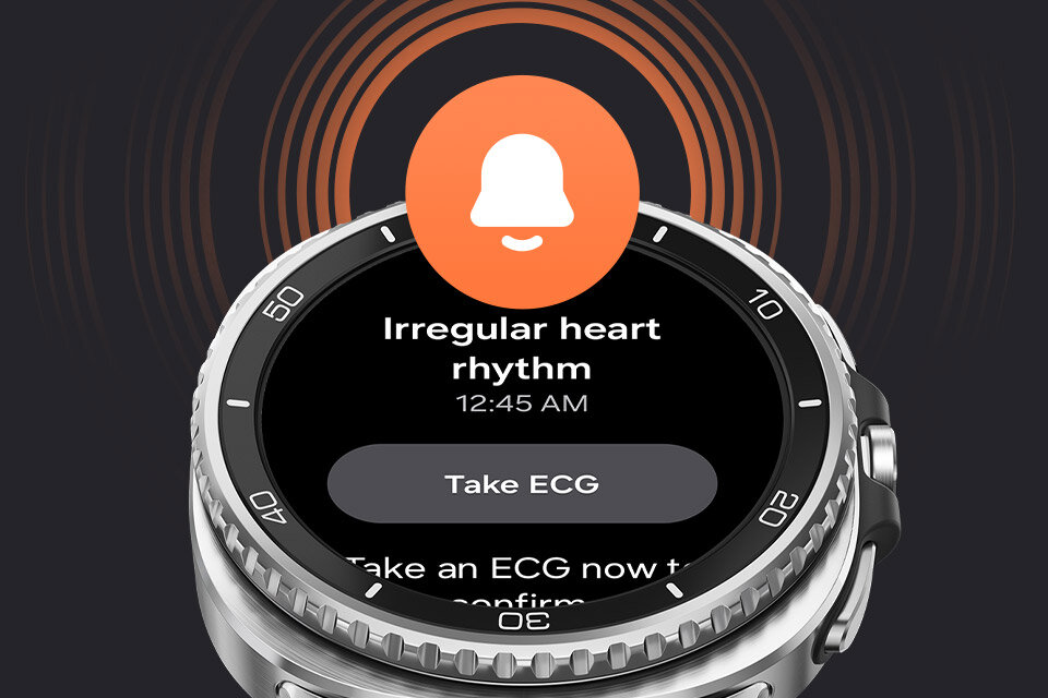 Smartwatch z okrągłym wyświetlaczem pokazuje powiadomienie o nieregularnym rytmie serca z opcją \'Take ECG\'. Na ekranie widoczna jest także godzina 12:45 AM oraz ikona dzwonka.