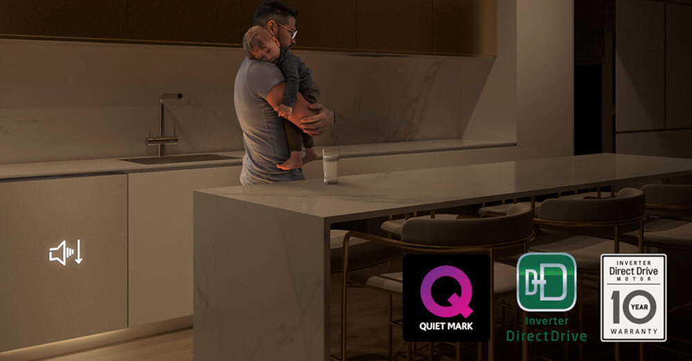 W kuchni stoi osoba trzymająca dziecko, obok znajduje się wyspa kuchenna. Na dole widoczne są trzy logotypy: \'Quiet Mark\', \'Inverter Direct Drive\', oraz \'Inverter Direct Drive Motor 10 Year Warranty\'.
