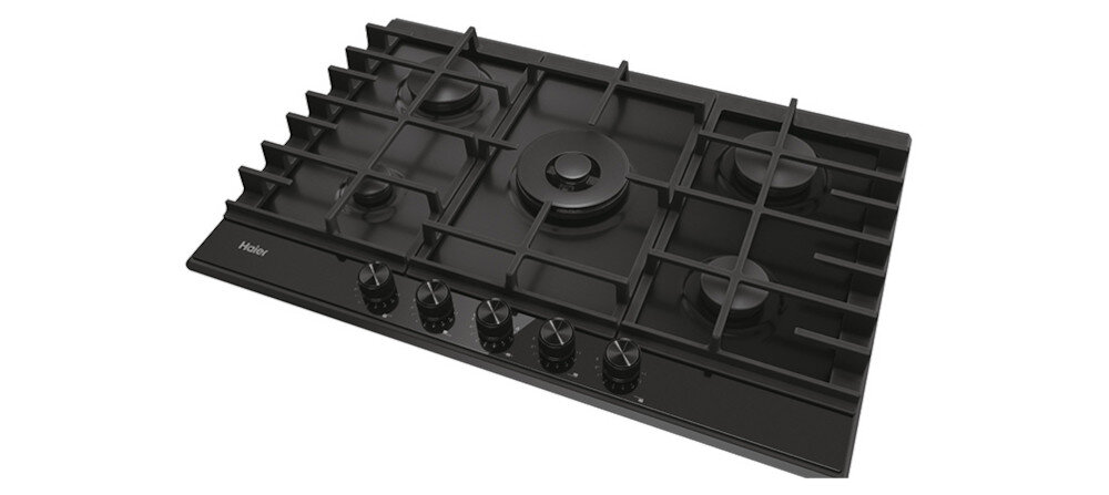 Czarna płyta gazowa z pięcioma palnikami i metalowymi rusztami. Na froncie znajduje się pięć pokręteł do regulacji gazu oraz logo Haier.
