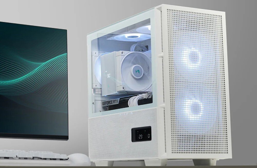 Komputer MAD DOG DEEPCOOL360-WH-A01DR32WH Biała obudowa komputera z przeszklonym bokiem stojąca na biurku obok monitora, ukazująca wewnątrz podświetlane na biało wentylatory i chłodzenie procesora z wyświetlaczem temperatury, a na dolnym panelu przednim widoczny jest mały ekran cyfrowy
