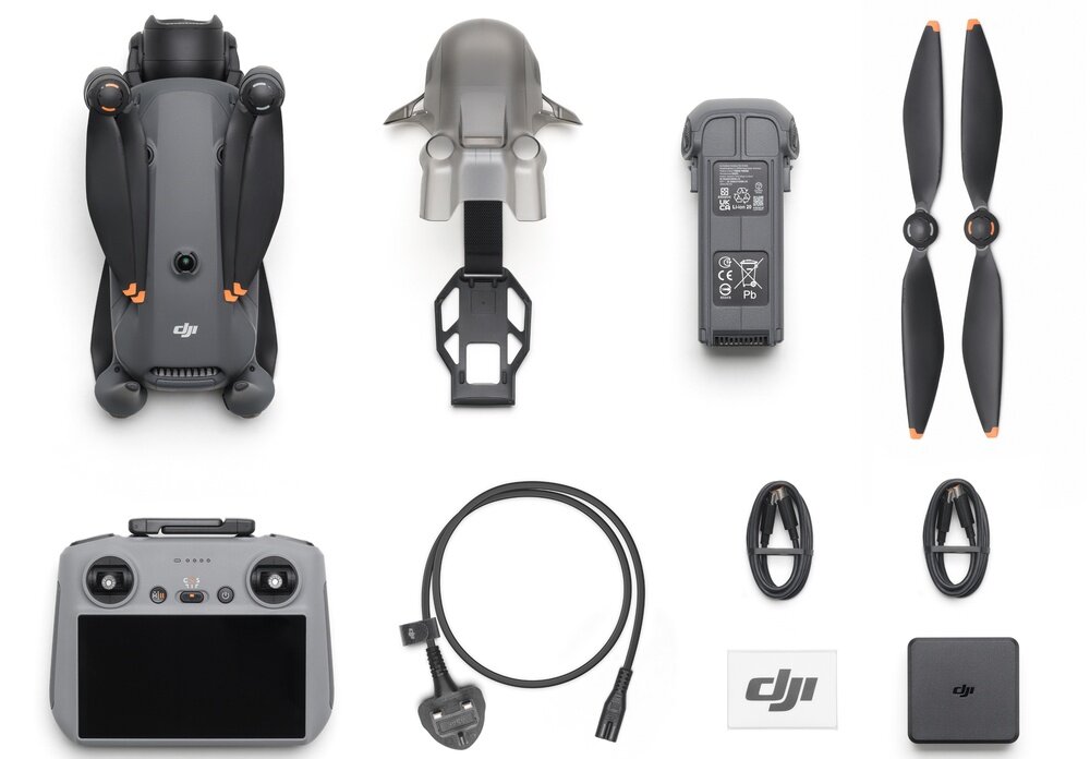 Na obrazie widoczny jest zestaw akcesoriów do drona, w tym złożony dron, osłona, bateria, śmigła, kontroler z ekranem, kabel zasilający oraz elementy montażowe. Logo \'DJI\' znajduje się na kilku elementach zestawu.