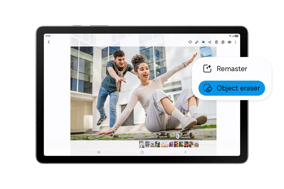 Tablet wyświetla zdjęcie dwóch osób na deskorolce przed budynkiem. Na ekranie widoczne są opcje \'Remaster\' i \'Object eraser\'.