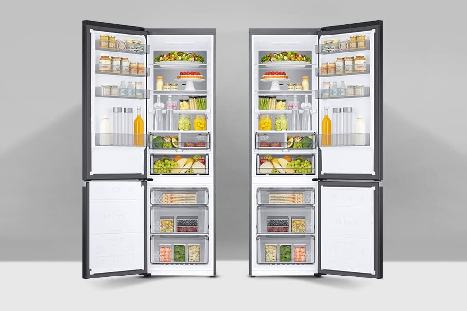 Dwie otwarte lodówki z widocznymi półkami wypełnionymi różnorodnymi produktami spożywczymi, takimi jak owoce, warzywa, napoje i słoiki. Wnętrze lodówek jest dobrze oświetlone, a drzwi mają ciemne obramowanie.