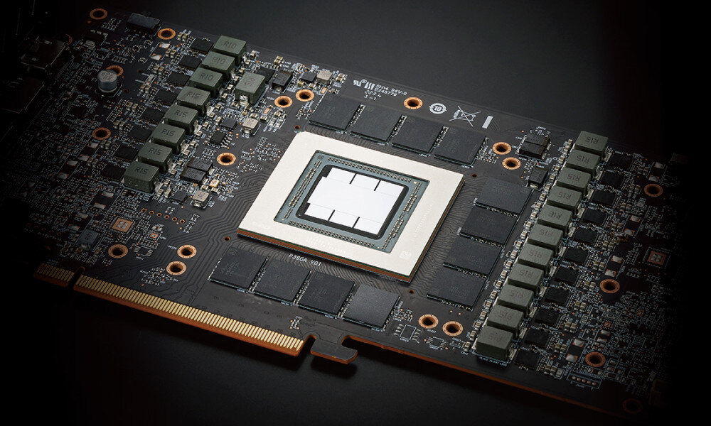 Zdjęcie przedstawia zbliżenie na płytę drukowaną karty graficznej z widocznymi elementami elektronicznymi i złączem PCIe. Na środku znajduje się duży, kwadratowy układ scalony otoczony mniejszymi komponentami.