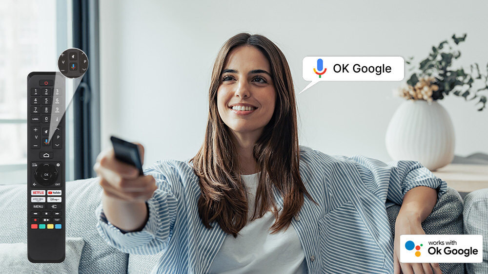 Osoba siedzi na kanapie, trzymając pilot w ręku, obok widoczny jest pilot z przyciskami do obsługi telewizora. Na obrazie znajduje się tekst \'OK Google\' oraz logo \'works with Ok Google\'.