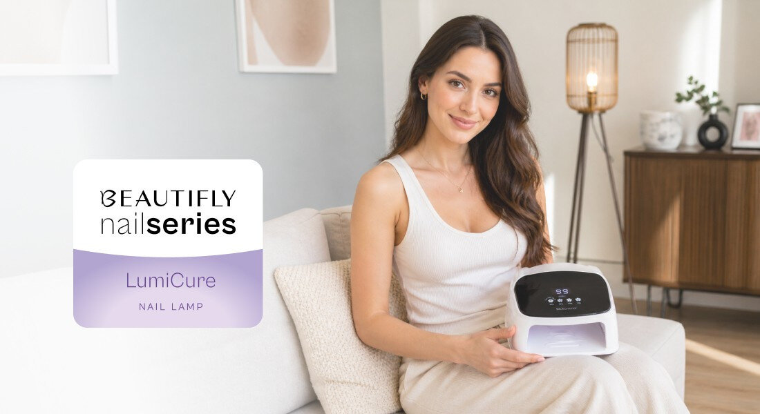 Kobieta siedzi na kanapie, trzymając lampę do paznokci z wyświetlaczem cyfrowym. Obok widoczny jest napis \'BEAUTIFLY nail series LumiCure NAIL LAMP\'.