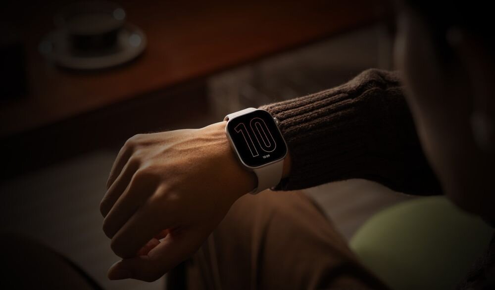Osoba nosi smartwatch z dużym wyświetlaczem, na którym widoczna jest liczba \'10\'.