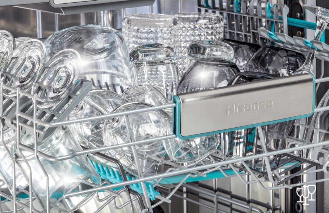 Wnętrze zmywarki z widocznymi szklankami i kieliszkami umieszczonymi w koszu. Na uchwycie kosza widnieje napis \'Hisense\'.