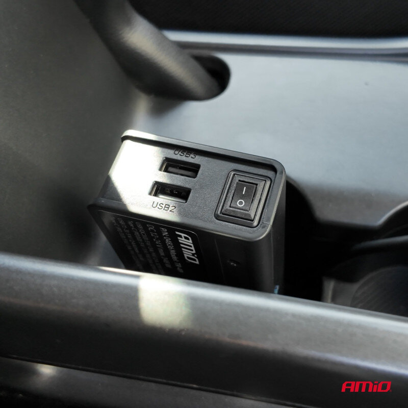 Na zdjęciu widoczny jest rozgałęźnik gniazda zapalniczki z dwoma portami USB oznaczonymi jako USB3 i USB2 oraz przełącznikiem z oznaczeniem I/O. W prawym dolnym rogu znajduje się logo AMiO.