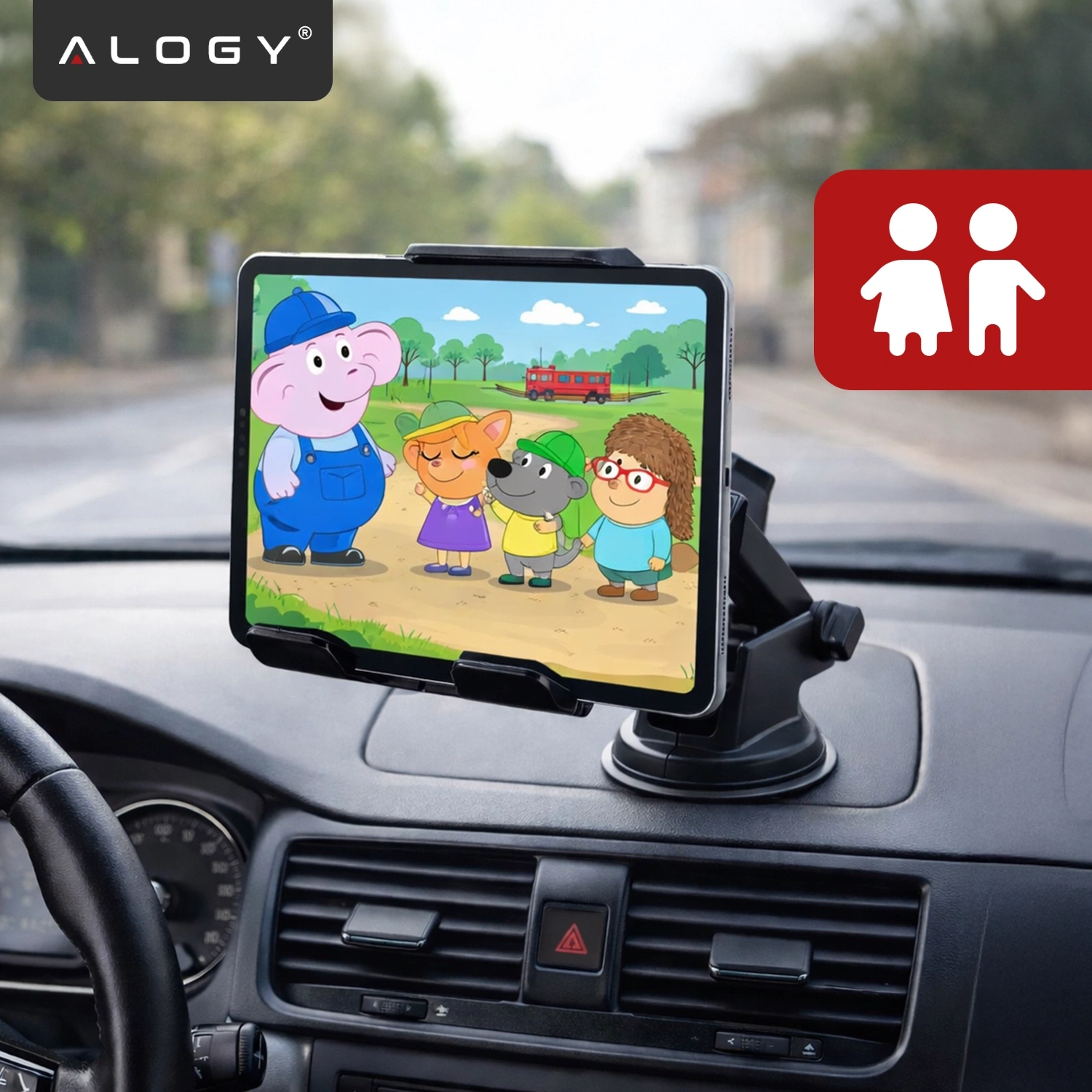 Uchwyt samochodowy zamontowany na desce rozdzielczej, trzymający tablet z wyświetloną kolorową grafiką z postaciami kreskówkowymi. W lewym górnym rogu widoczne jest logo \'ALOGY\'.