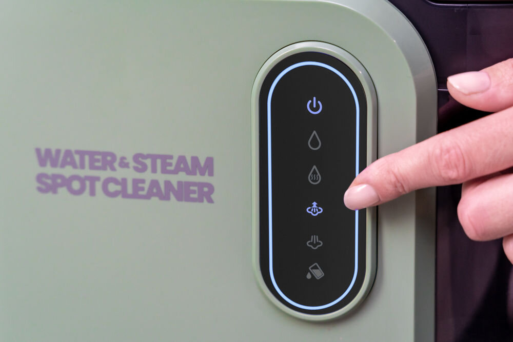 ODKURZACZ PIORĄCY SPOTCLEAN GOTZE&JENSEN CSC600 z ekranem LED komunikatami głosowymi powiadomieniem o pełnym zbiorniku intuicyjną obsługą Bardzo bliskie ujęcie panelu sterowania odkurzacza piorącego. Ręka dotyka wskaźnika LED, prawdopodobnie do uruchomienia funkcji pary. Na panelu są ikony: włącznik, kropla wody, para (trzy fale), strumień pary, wciąganie cieczy i pojemnik na brudną wodę. Widać napis: WATER & STEAM SPOT CLEANER.