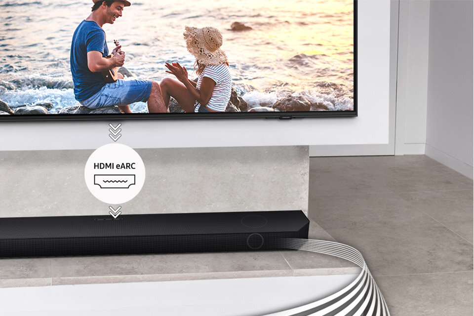 Na obrazie widać czarny soundbar umieszczony pod telewizorem, na którym wyświetlany jest obraz pary siedzącej nad wodą. Nad soundbarem znajduje się symbol z napisem \'HDMI eARC\'.