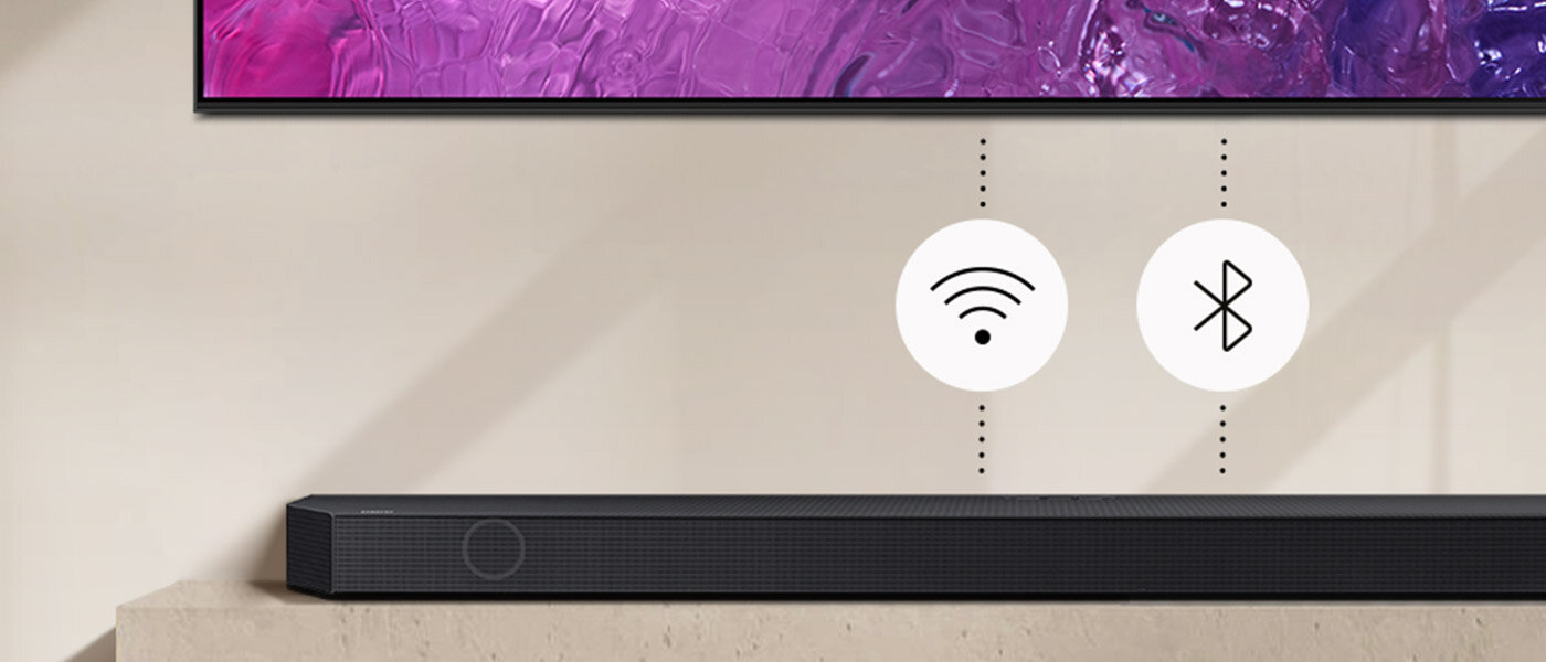 Czarny soundbar umieszczony na jasnej powierzchni, nad nim widoczne są ikony Wi-Fi i Bluetooth na białych okręgach.