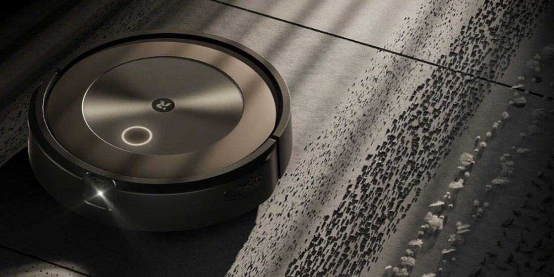 Robot sprzątający porusza się po podłodze, pozostawiając czystą powierzchnię. Na obudowie widoczne jest logo producenta.