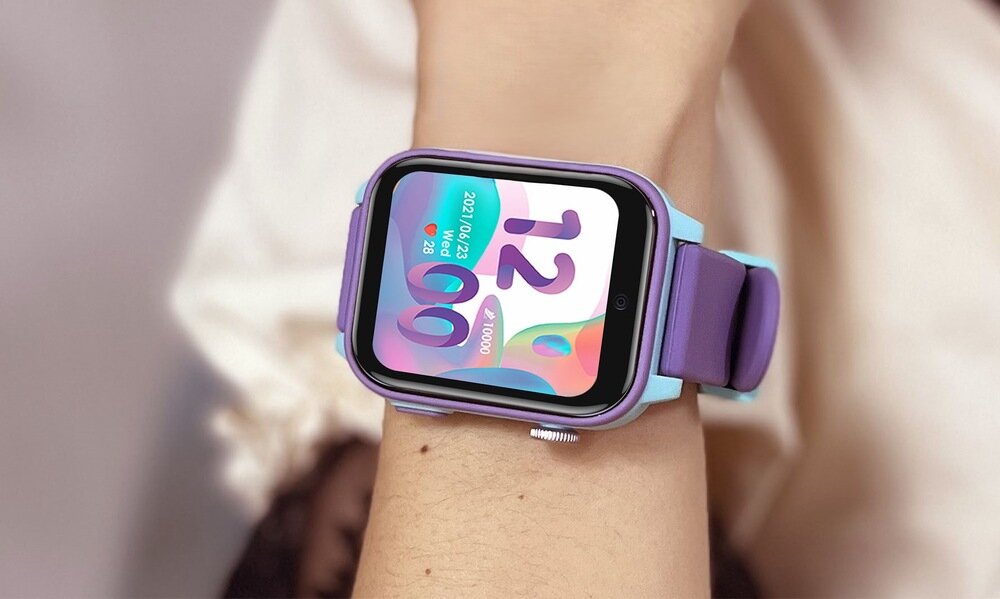 Na zdjęciu widoczny jest smartwatch z kolorowym wyświetlaczem, na którym widać godzinę 12:00 oraz datę 2023-10-23. Pasek zegarka jest w kolorze fioletowym.