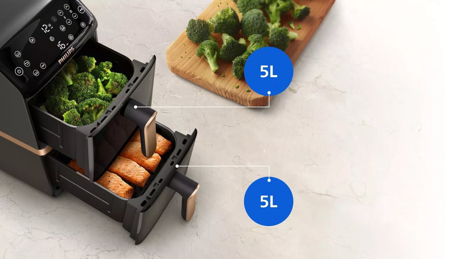 Na obrazie widoczna jest frytkownica beztłuszczowa z dwoma otwartymi koszami, w których znajdują się brokuły i kawałki łososia. Na desce obok leżą dodatkowe kawałki brokułów, a przy koszach widoczne są oznaczenia \'5L\'.