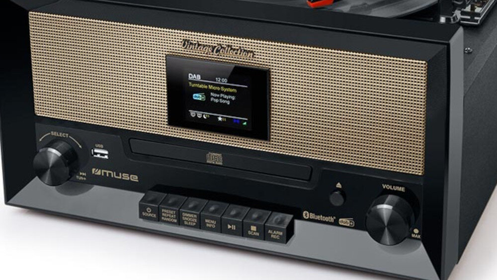 Czarny gramofon z wyświetlaczem pokazującym tekst: \'DAB 12:00 Turntable Micro System Now Playing Pop Song\'. Na panelu widoczne są przyciski i pokrętła oraz logo \'muse\'.