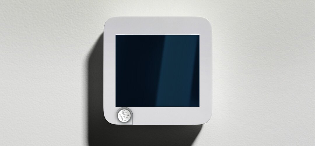 Nowoczesny biały panel z ciemnym ekranem, bateria VARTA CR2032 widoczna w dolnym rogu urządzenia.